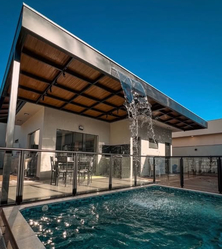 Varanda gourmet com piscina e cobertura metálica com cascata